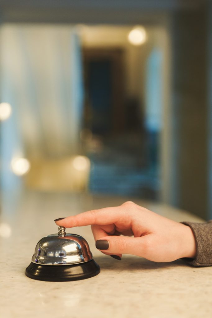 Woman ringing hotel reception service bell closeup